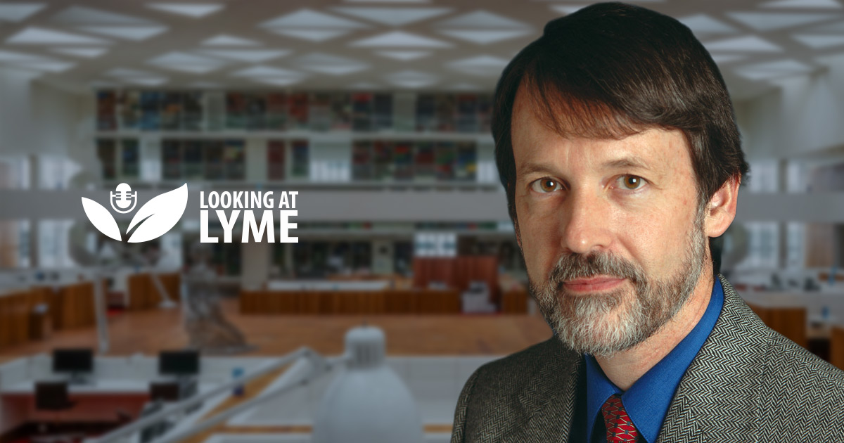 Dr. Brian Fallon, MD, with the Looking at Lyme logo, in front of a library.