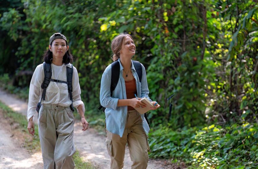 Two young people go hiking and wear long pants that are light coloured.