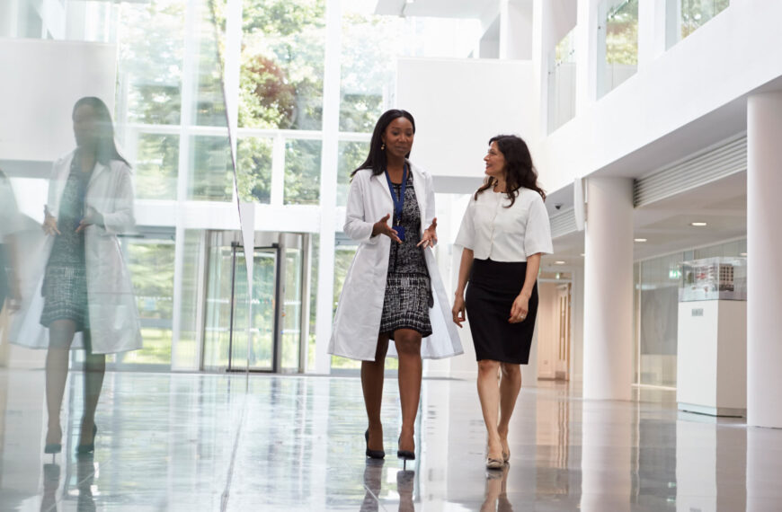 Two women walk down the hall in a large research facility.