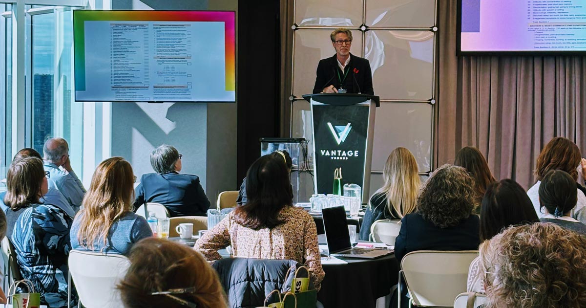 Dr Tim Cook stands at the front of the conference delivering his presentation.