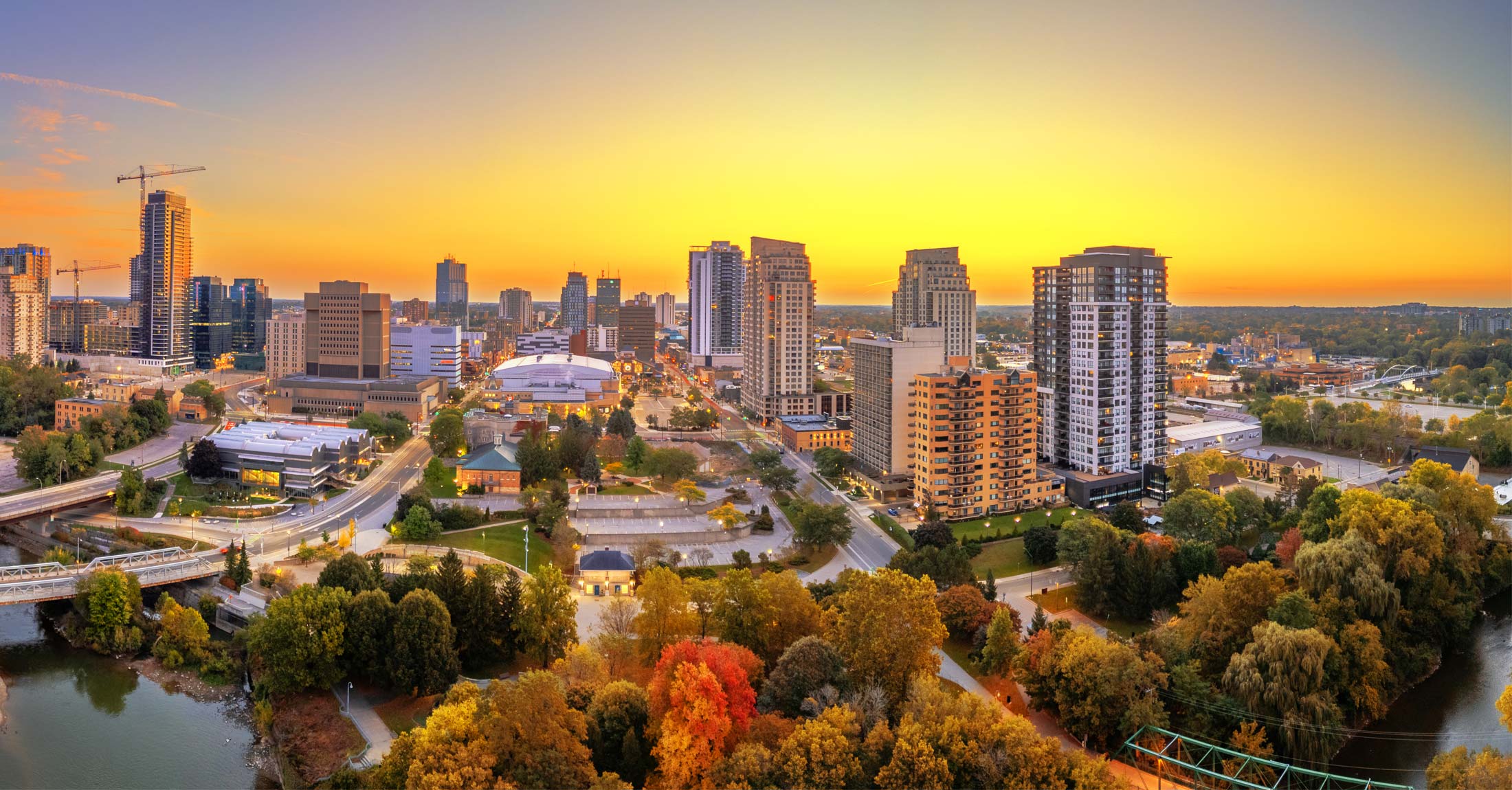 The sun sets over London Ontario in the autumn with vivid yellow and red glowing around the city scape.